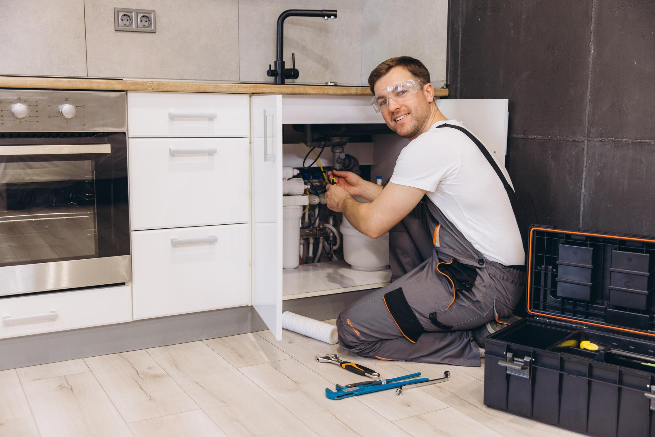 A plumber working under a kitchen sink